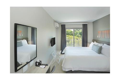 Habitación de hotel con 2 camas y espejo en The Capital on Bath en Johannesburgo