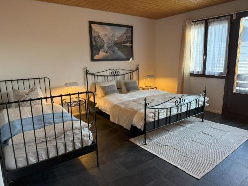 two beds in a bedroom with two windows at Casa14 - Swiss houses in Steffisburg