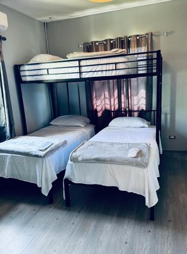 two bunk beds sitting in a room with wooden floors at home away from home in Diego Martin