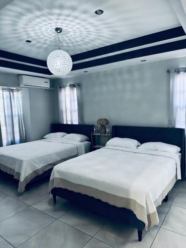 two beds in a bedroom with blue and white walls at home away from home in Diego Martin