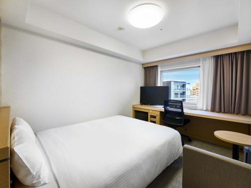 a hotel room with a bed and a desk and a window at Daiwa Roynet Hotel Naha Kokusaidori in Naha