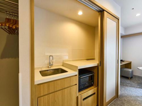 a small kitchen with a sink and a microwave at Daiwa Roynet Hotel Naha Kokusaidori in Naha