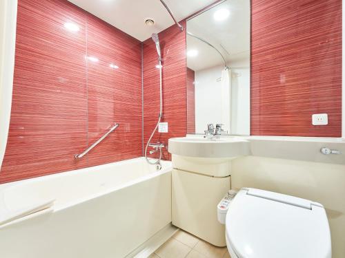a bathroom with a toilet and a tub and a sink at Daiwa Roynet Hotel Naha Kokusaidori in Naha