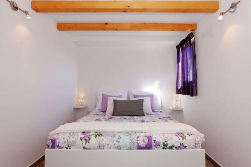 a small bedroom with a bed with purple bedding at Family friendly house with a swimming pool Bol, Brac - 23787 in Bol