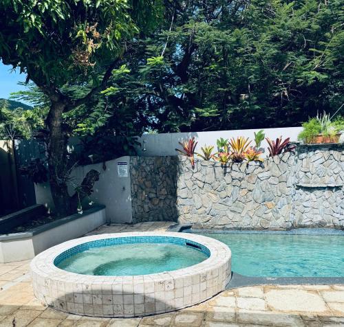 a hot tub in a stone wall next to a swimming pool at home away from home in Diego Martin