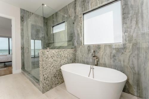a bathroom with a white tub and a shower at Waterfront Home with Pool Spacious Bay , Sleeps 16 in Port Isabel