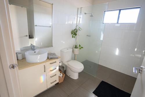 a bathroom with a toilet and a sink and a mirror at Suburban Sanctuary South Hedland in South Hedland
