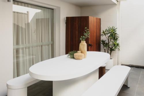a white dining room with a white table and benches at Yarra Valley Grand in Yarra Glen