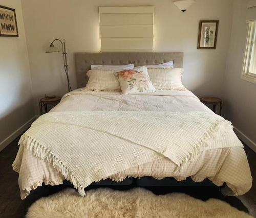 a bedroom with a large bed with a white comforter at The Rustic Nest Yarramalong in Yarramalong