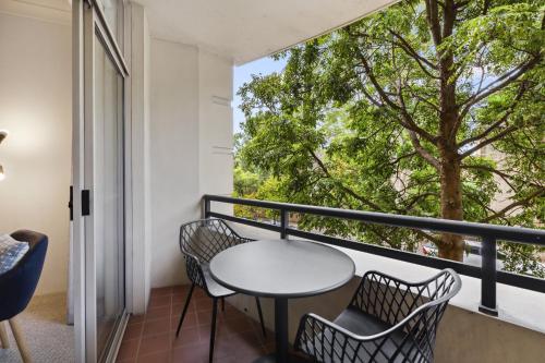 a balcony with a table and chairs and a large window at Chic Urban Escape in Vibrant Camperdown in Sydney