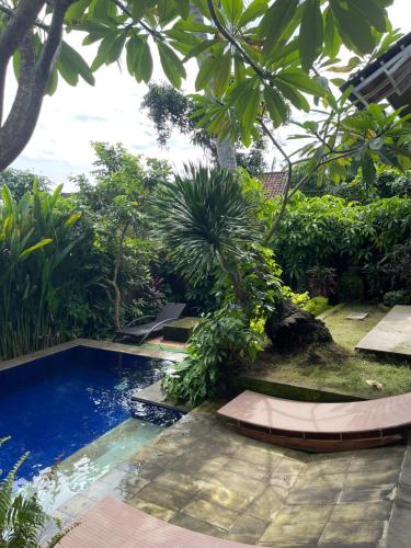 a swimming pool in the middle of a garden at Pranajaya loka villa in Tejakula