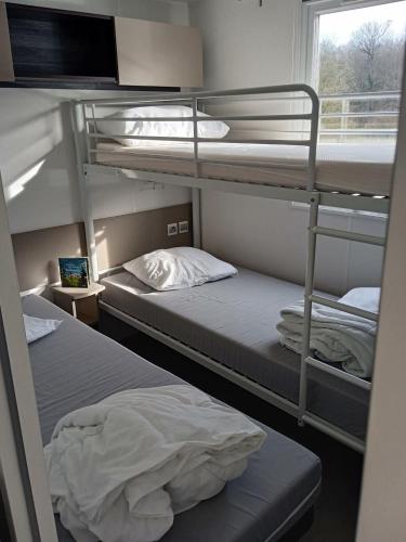 deux lits superposés dans une chambre avec fenêtre dans l'établissement Joli mobilhome 7 places, 3 chambres Blois Amboise Piscine, à Onzain