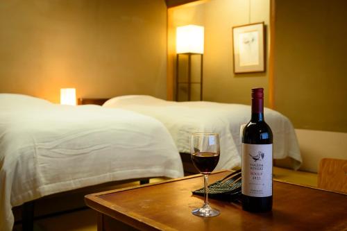 a bottle of wine sitting on a table with a glass at Senkeien Tsukioka Hotel in Kaminoyama