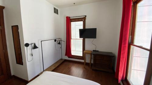 a bedroom with a bed and a television and a window at ITH San Diego Adventure Hostel in San Diego