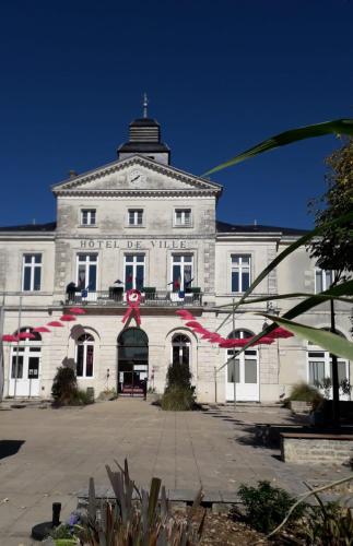 a large white building with a red ribbon in front at Au Coin Maison in Ruffec
