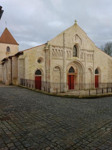 a large brick building with red doors and a fence at Au Coin Maison in Ruffec
