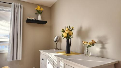 a white counter with flowers in a vase on it at Family Friendly 3 Bedroom Unit - Close to Downtown Kingston! in Kingston
