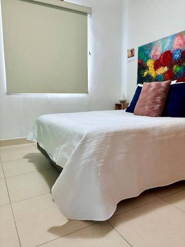 a bedroom with a white bed with a painting on the wall at Casa Privada 2hab San Pedro cerca consulado Americana in Monterrey