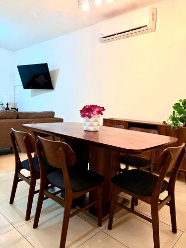 a wooden table with chairs and a vase of flowers on it at Casa Privada 2hab San Pedro cerca consulado Americana in Monterrey