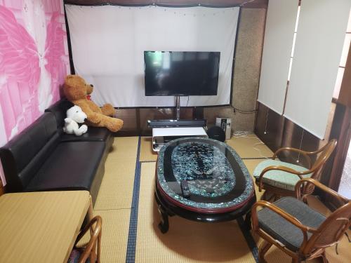 a teddy bear sitting on a couch in a living room at Full House-貸切-電車成田空港30分 in Inzai