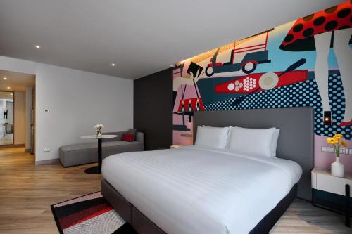 a bedroom with a white bed and a painting on the wall at Oakwood Studios Sukhumvit Bangkok in Bangkok