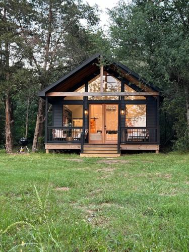 a small cabin in a field with a large window at Relaxing Modern stay on a Ranch in Cedar Creek