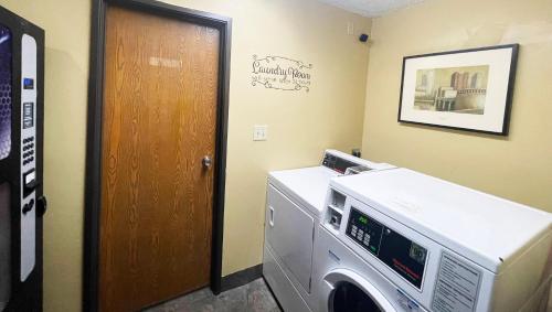 a laundry room with a washing machine and a door at Magnuson Hotel Fort Wayne North - Coliseum in Fort Wayne