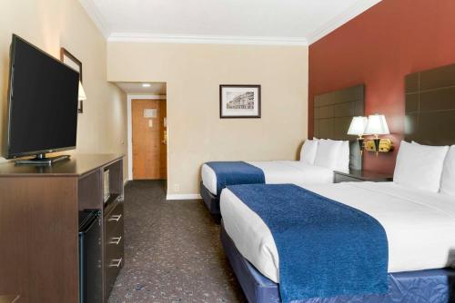 a hotel room with two beds and a flat screen tv at Best Western Greenfield Inn in Allen Park