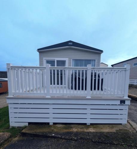 a white house with a white railing on the porch at Bright, modern & stylish deluxe caravan located on the very popular Swanage bay view holiday park in Swanage