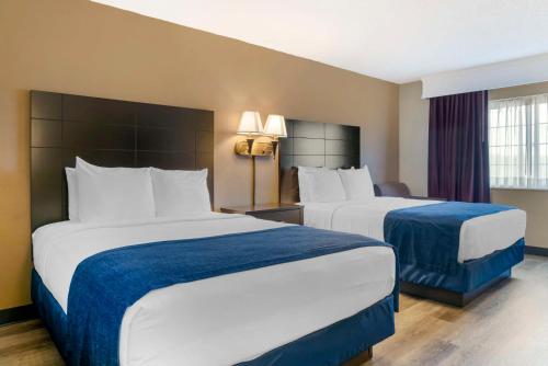 a hotel room with two beds with blue and white sheets at Best Western Greenfield Inn in Allen Park