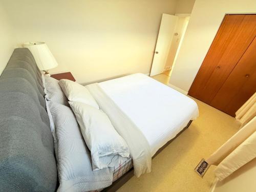 a bedroom with a bed with white sheets and a lamp at Cozy main floor, 03 Bedrooms, close to Downtown REGINA in Regina