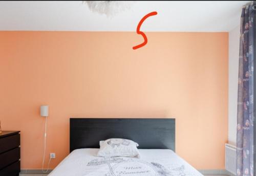 une chambre avec un lit avec un mur orange dans l'établissement Appart cosy Marseille, à Marseille