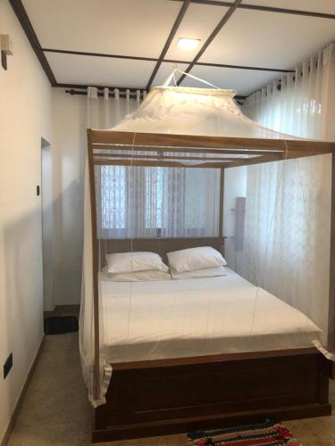 a canopy bed with white sheets and pillows on it at Murphy's Transit Villa Airport Pick & Drop Katunayake in Katunayake