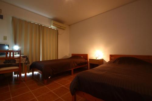 a bedroom with two beds and a desk and a window at AsobiBASE Yamabare-House in Ishigaki Island