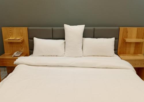 a large bed with white sheets and pillows at Leading Continental Hotel - Muzaffarabad AJK in Muzaffarabad