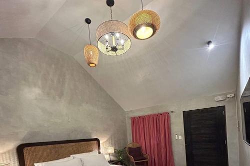 a bedroom with a bed and two lights and a ceiling at Balai Balatong Ilocos near Laoag Airport in Raraburan