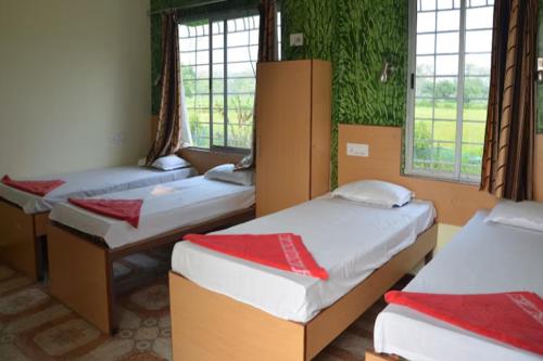 a room with three beds and two windows at Banolata Lakeside Homestay by StayApart in Damanpur