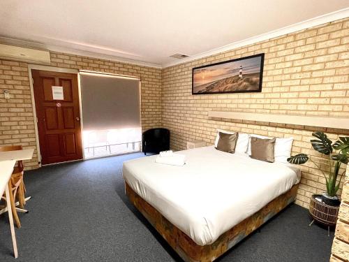 a bedroom with a large bed in a brick wall at Drakesbrook Hotel in Waroona