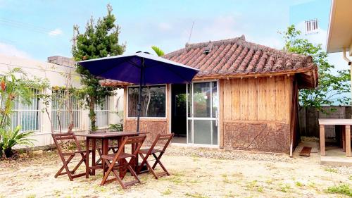 a table and chairs with an umbrella in front of a house at NEWOPEN Villa lanikai in Kabira