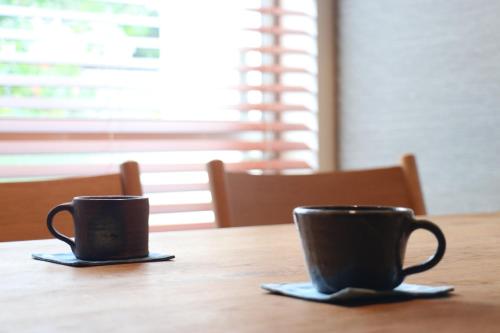 two coffee cups sitting on top of a wooden table at NEWOPEN Villa lanikai in Kabira