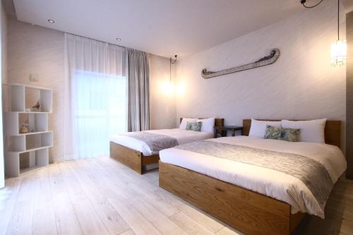 a hotel room with two beds and a window at NEWOPEN Villa lanikai in Kabira