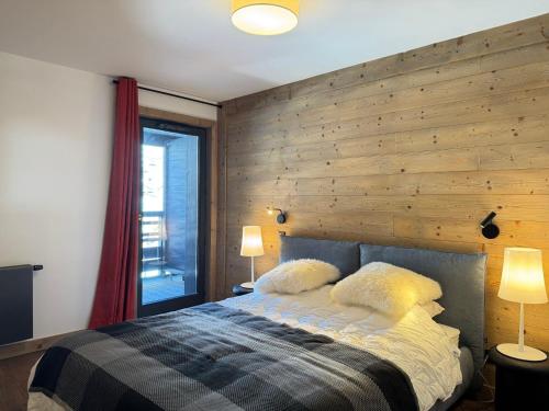 - une chambre avec un lit et un mur en bois dans l'établissement Appartement lumineux au cœur des Gets avec balcon et parking - FR-1-623-222, aux Gets