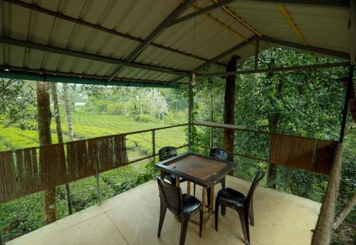 - une table et des chaises sur une terrasse couverte offrant une vue sur la forêt dans l'établissement Vythiri Hill Palace, à Vythiri