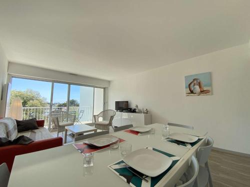 - un salon avec une table blanche, des chaises et un canapé dans l'établissement Appartement 4 pièces/6 couchages proche plage - LE POULIGUEN - FR-1-245-210, au Pouliguen