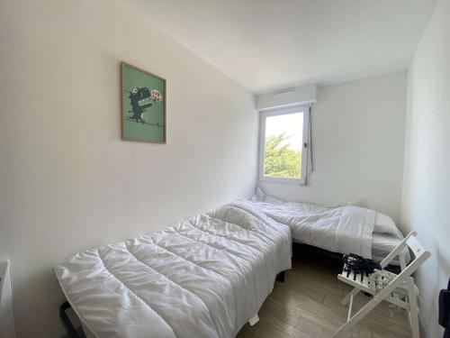 une chambre avec deux lits et une fenêtre dans l'établissement Appartement 4 pièces/6 couchages proche plage - LE POULIGUEN - FR-1-245-210, au Pouliguen