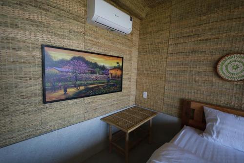 a bedroom with a painting on the wall and a table at Hành Ngò Homestay - Hòn Đỏ Ninh Thuận in Thôn Dư Khánh