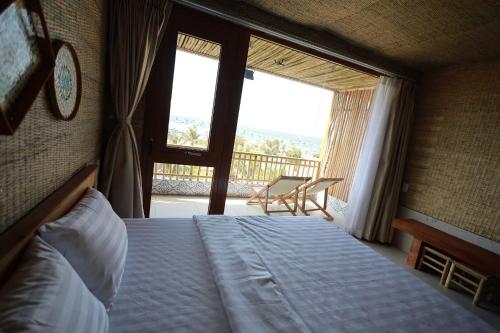 a bedroom with a bed and a window with a balcony at Hành Ngò Homestay - Hòn Đỏ Ninh Thuận in Thôn Dư Khánh