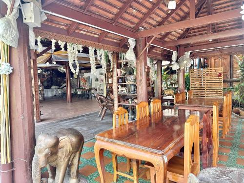 a dining room with a wooden table and an elephant statue at Montri Resort Donmuang Bangkok in Bangkok