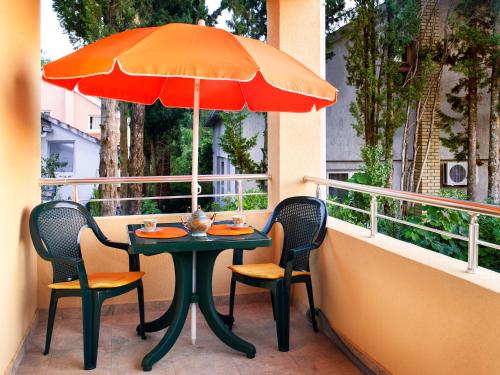 a table with two chairs and an umbrella on a balcony at Apartments Viktoria in Tivat