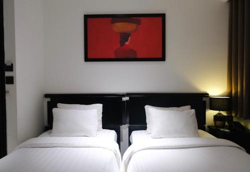 two beds in a room with a painting on the wall at Nicecy Boutique Hotel in Ho Chi Minh City